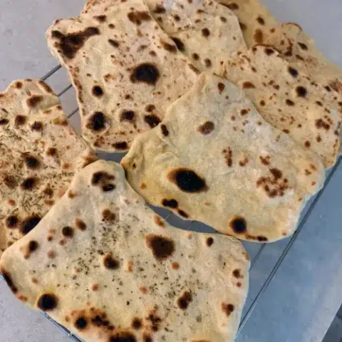 Soft homemade vegan naan bread garnished with fresh herbs
