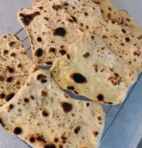 Soft homemade vegan naan bread garnished with fresh herbs
